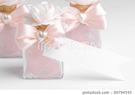 Rectangle strip white tag mockup with pink wedding favor on a white background, decorative bottle with gift tag mockup 89794595