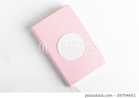 Round sticker mockup, circle white adhesive label mockup in pink book on a white background 89794601