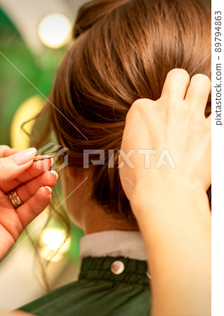 Hairstyling bride. A female hairdresser makes styling hair for the beautiful young caucasian woman in a beauty salon 89794863