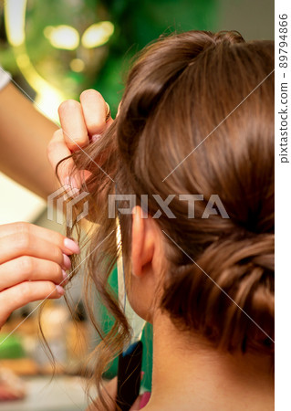 Hairstyling bride. A female hairdresser makes styling hair for the beautiful young caucasian woman in a beauty salon 89794866
