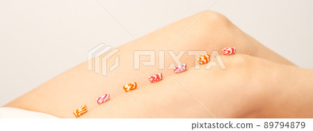 Depilation, waxing concept. Round candies lying down in a row on the female leg, close up Depilation, waxing concept. Round candies lying down in a row on the female leg, close up 89794879