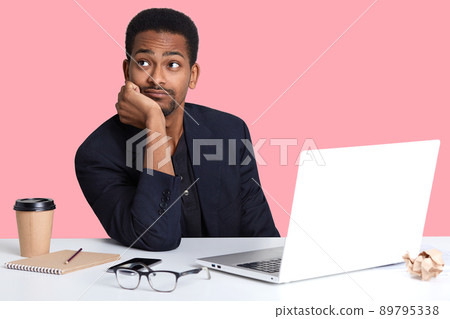 Close up portrait of thoughtful african american businessman thinking about having rest and relaxing, dreaming about something, while working with lap top, uses wireless Internet. Tecchnology concept. Close up portrait of thoughtful african american businessman thinking about having rest and relaxing, dreaming about something, while working with lap top, uses wireless Internet. Tecchnology concept. 89795338