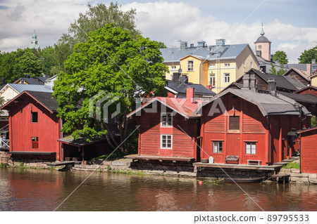 Old red wooden houses and barns stand along the river coast in old town Old red wooden houses and barns stand along the river coast in old town 89795533