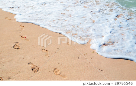 Bare footprints and shore foam are over wet beach sand, summer vacation Bare footprints and shore foam are over wet beach sand, summer vacation 89795546