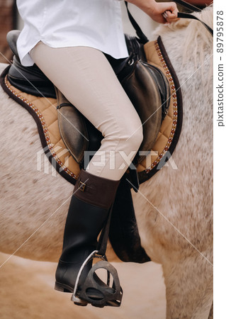 Close-up of a rider's legs in stirrups. A woman on a horse 89795878