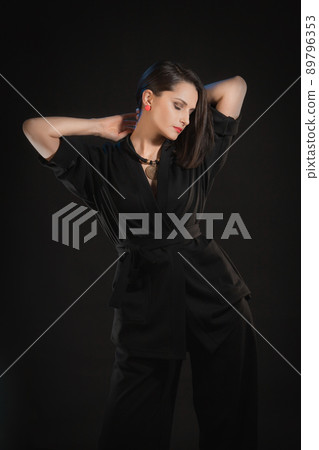 Brunette woman posing in black silk kimono with raised hands on a black background 89796353