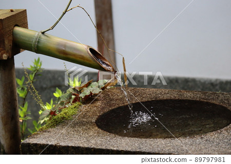 A landscape where water flows from a bamboo tsukubai and splashes on the surface of a stone chozubachi 89797981