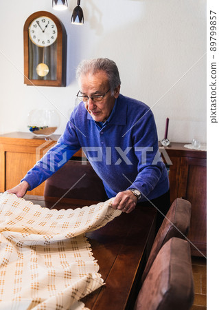 Grandfather putting the tablecloth on the table for eating Grandfather putting the tablecloth on the table for eating 89799857