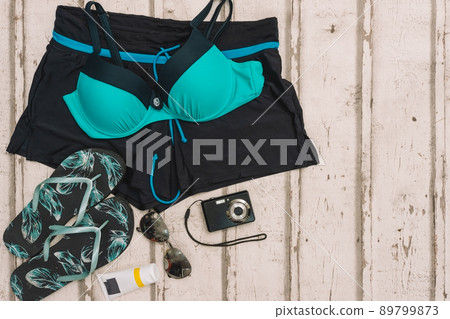 top view beach objects. swimming costume, flip-flops, sunglasses and compact camera for holidays. 89799873