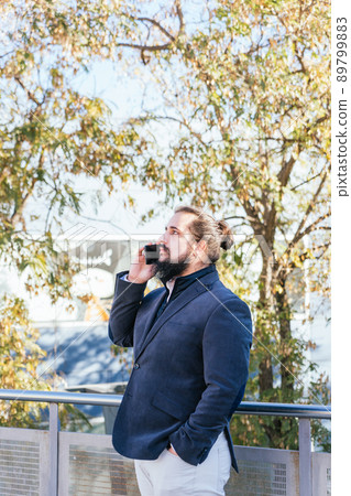 Young business man talking mobile next to the offices Young business man talking mobile next to the offices 89799883