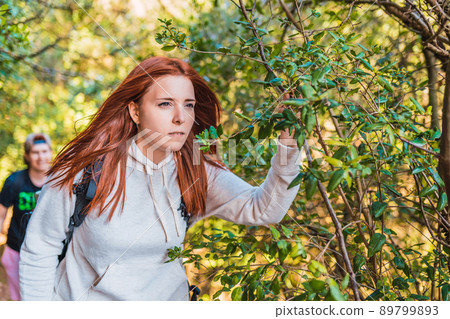 young red-haired woman walking in nature, contemplating the horizon. woman hiker on the road. young people on a trip. 89799893