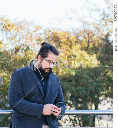 Young business man looking mobile next to the offices 89799952