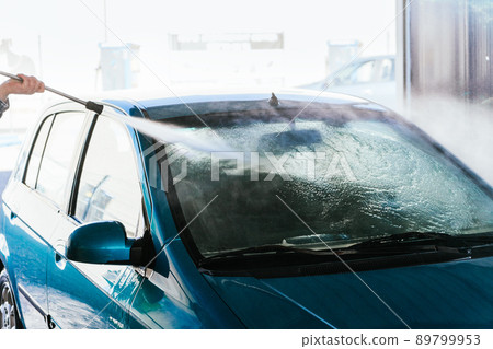 Detail of washing the front of a car with a hosepipe 89799953
