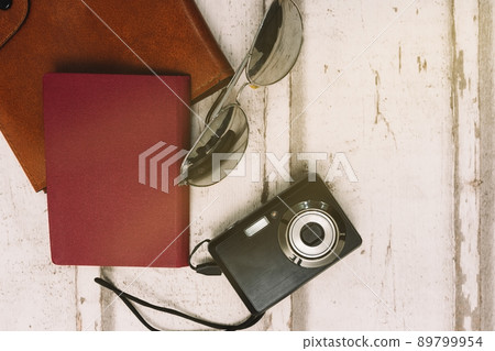 top view still life travel. Light wood background. Personal documents, passport, sunglasses and compact camera for holidays. 89799954