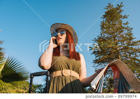 young red-haired girl calling with her smart phone for a taxi to pick her up at her resort. travel, summer holiday, young red-haired girl calling with her smart phone for a taxi to pick her up at her resort. travel, summer holiday, 89799974
