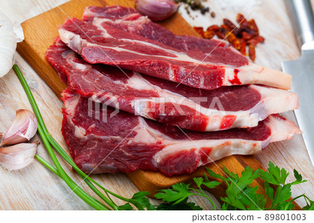 Sliced raw veal steak with fresh parsley Sliced raw veal steak with fresh parsley 89801003