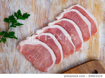 Preparation of raw pork loin on a wooden board Preparation of raw pork loin on a wooden board 89801016