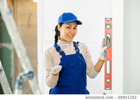 Woman worker measuring wall with spirit level 89801292