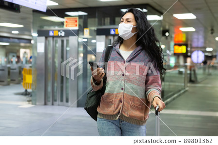 Woman in face mask with backpack walking in subway beside escolator Woman in face mask with backpack walking in subway beside escolator 89801362