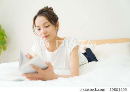 A woman relaxing in bed A woman relaxing in bed 89801803