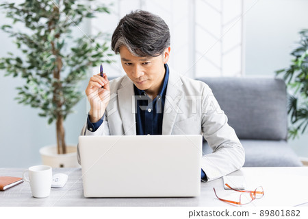 A businessman doing desk work in a bright room with a sofa 89801882
