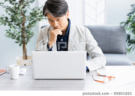 A businessman doing desk work in a bright room with a sofa 89801883