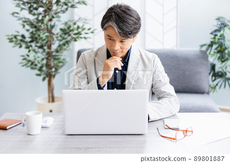 一個商人在帶沙發的明亮房間裡做辦公桌工作 一個商人在帶沙發的明亮房間裡做辦公桌工作 89801887