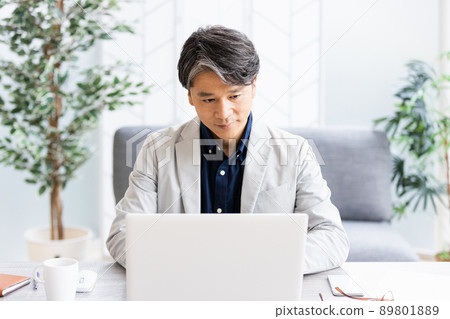 A businessman doing desk work in a bright room with a sofa 89801889