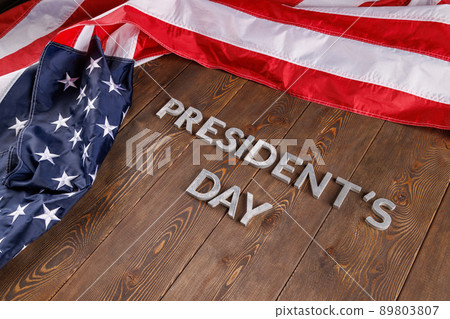 words presitdents day laid with silver letters on wooden surface near US flag 89803807