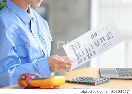 An engineer woman holding a drawing and pointing at the board to check 1 89803967