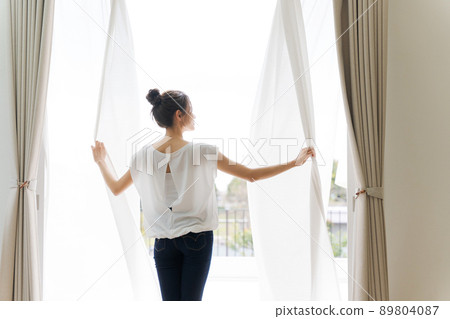 Woman opening the curtain at home 89804087