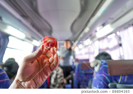 Strawberry with vanilla ice-cream inside are held by man hand in the bus. 89804165