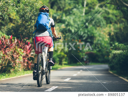 Woman cycling on tropical park trail in summer 89805137