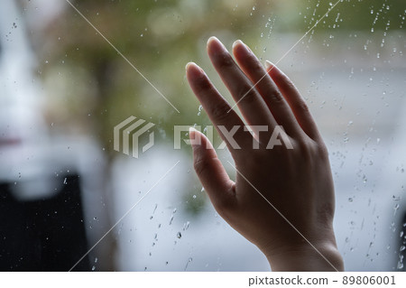 Female hands placed on the window of raindrops 89806001