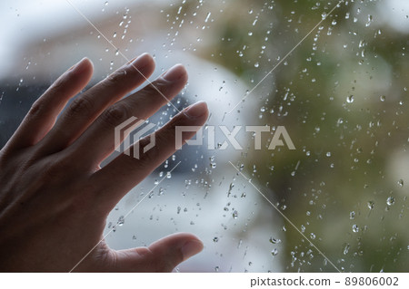 Female hands placed on the window of raindrops 89806002
