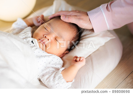 晚上睡覺，媽媽撫摸著她的頭，還有一個熟睡的嬰兒 89808698