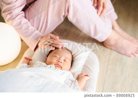 晚上睡覺,媽媽撫摸著她的頭,還有一個熟睡的嬰兒 晚上睡覺,媽媽撫摸著她的頭,還有一個熟睡的嬰兒 89808925