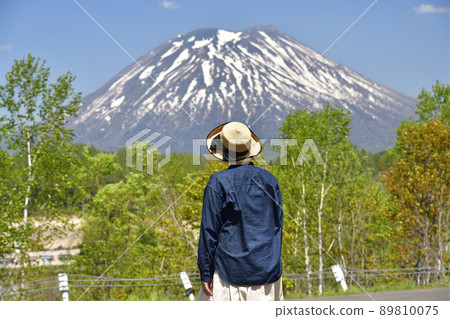 Taking a picture of Mt. Yotei with snow and a woman at the viewpoint in Niseko Town, Hokkaido in early summer 89810075