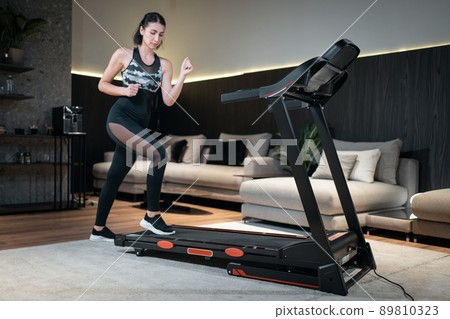 female feet running on treadmill in sport shoes, close up 89810323