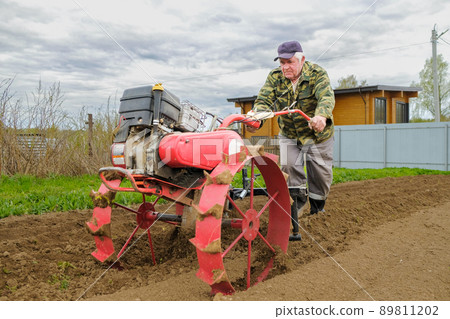 The farmer cultivates the soil for planting potatoes. The farmer cultivates the soil for planting potatoes. 89811202