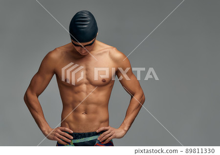 Portrait of a swimmer in a cap and mask, half-length portrait, young athlete swimmer wearing a cap and mask for swimming, copies of space, gray background. Portrait of a swimmer in a cap and mask, half-length portrait, young athlete swimmer wearing a cap and mask for swimming, copies of space, gray background. 89811330