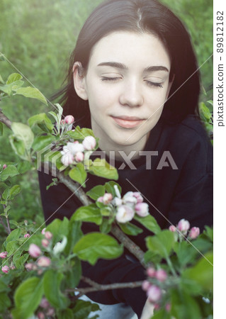 Pretty teen girl are posing in garden near blossom apple tree with pink flowers. Pretty teen girl are posing in garden near blossom apple tree with pink flowers. 89812182