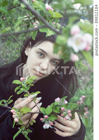 Pretty teen girl are posing in garden near blossom apple tree with pink flowers. Pretty teen girl are posing in garden near blossom apple tree with pink flowers. 89812184