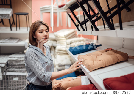 An Asian woman is selecting a seat cushion at the mall. An Asian woman is selecting a seat cushion at the mall. 89812532