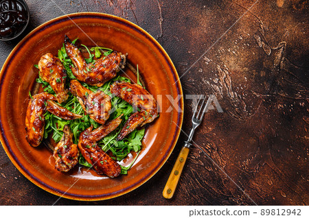 Bbq buffalo chicken wings on a plate with arugula. Dark background. Top view. Copy space Bbq buffalo chicken wings on a plate with arugula. Dark background. Top view. Copy space 89812942