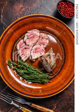 Grilled and sliced lamb fillet meat steak on a plate. Dark background. Top view Grilled and sliced lamb fillet meat steak on a plate. Dark background. Top view 89812962