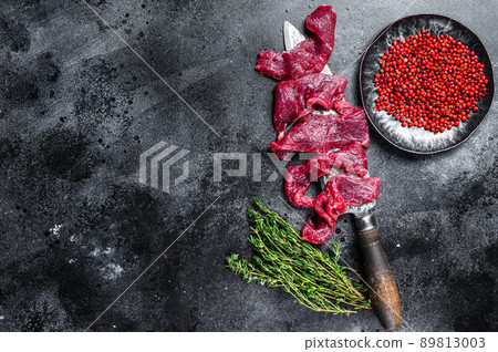Fresh beef marbled meat cut into thin strips for goulash. Black background. Top view. Copy space 89813003