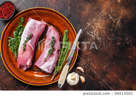 Fresh pork tenderloin meat with rosemary and thyme. Dark background. Top view. Copy space 89813083
