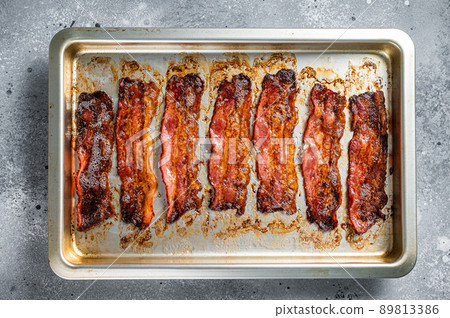 Strips of fried bacon in baking dish. Gray background. Top view Strips of fried bacon in baking dish. Gray background. Top view 89813386