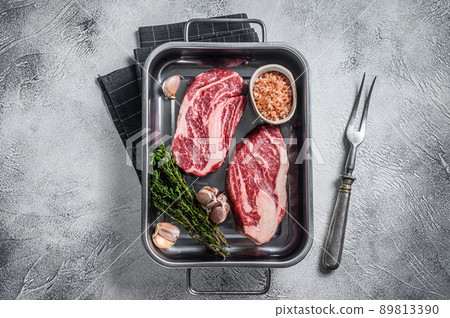 Uncooked Raw chuck eye roll steaks in a steel kitchen tray. Gray background. Top view 89813390